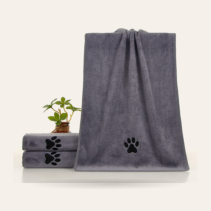 Serviette microfibre grise brodée d'une empreinte de patte, avec une plante et des serviettes empilées