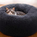 Chat blotti dans un lit rond en peluche gris foncé