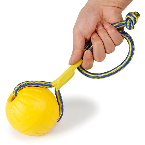 Une main tient la corde d'une balle jaune